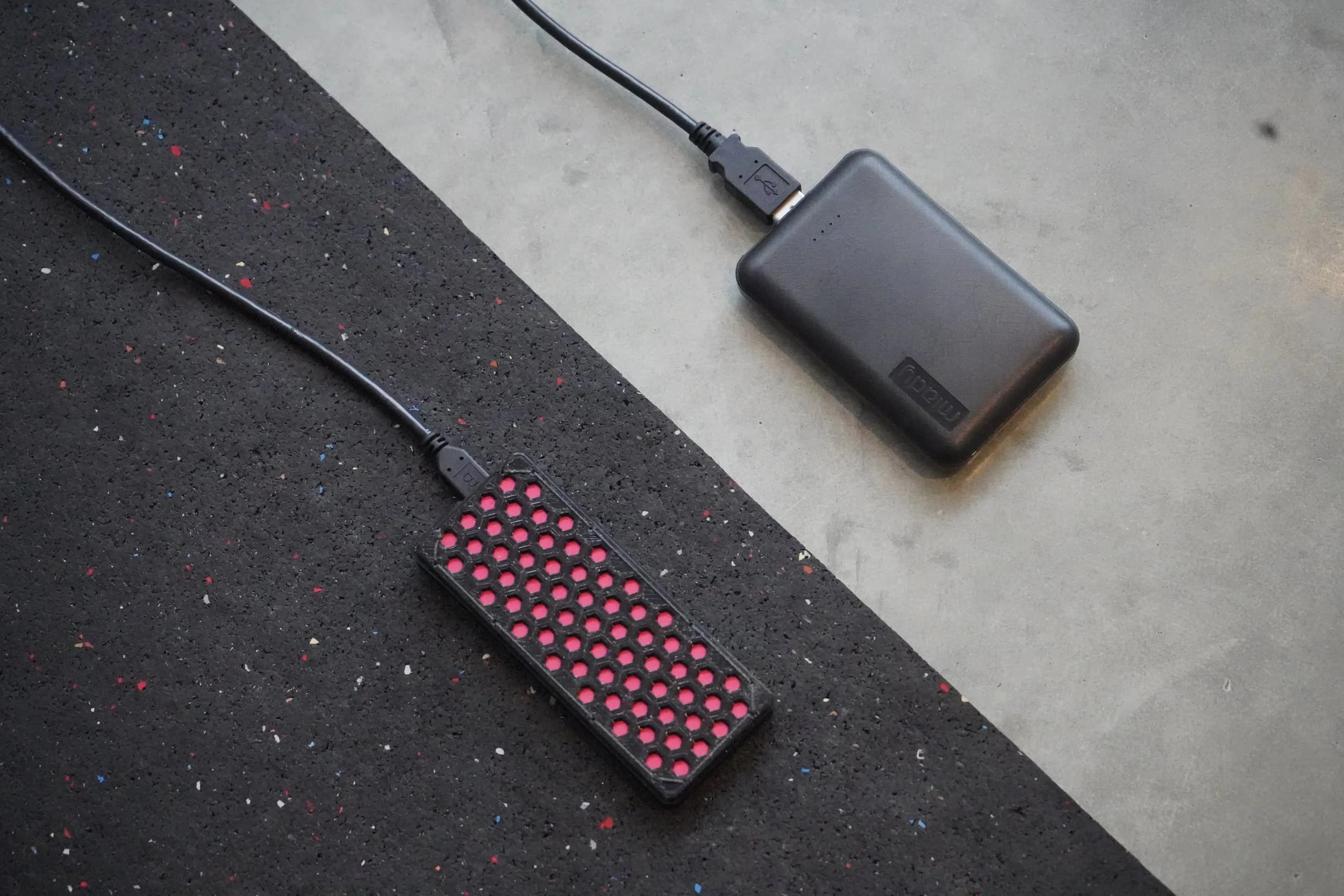 Close-up of the Vault platform's red-dotted sensor unit beside its battery pack.